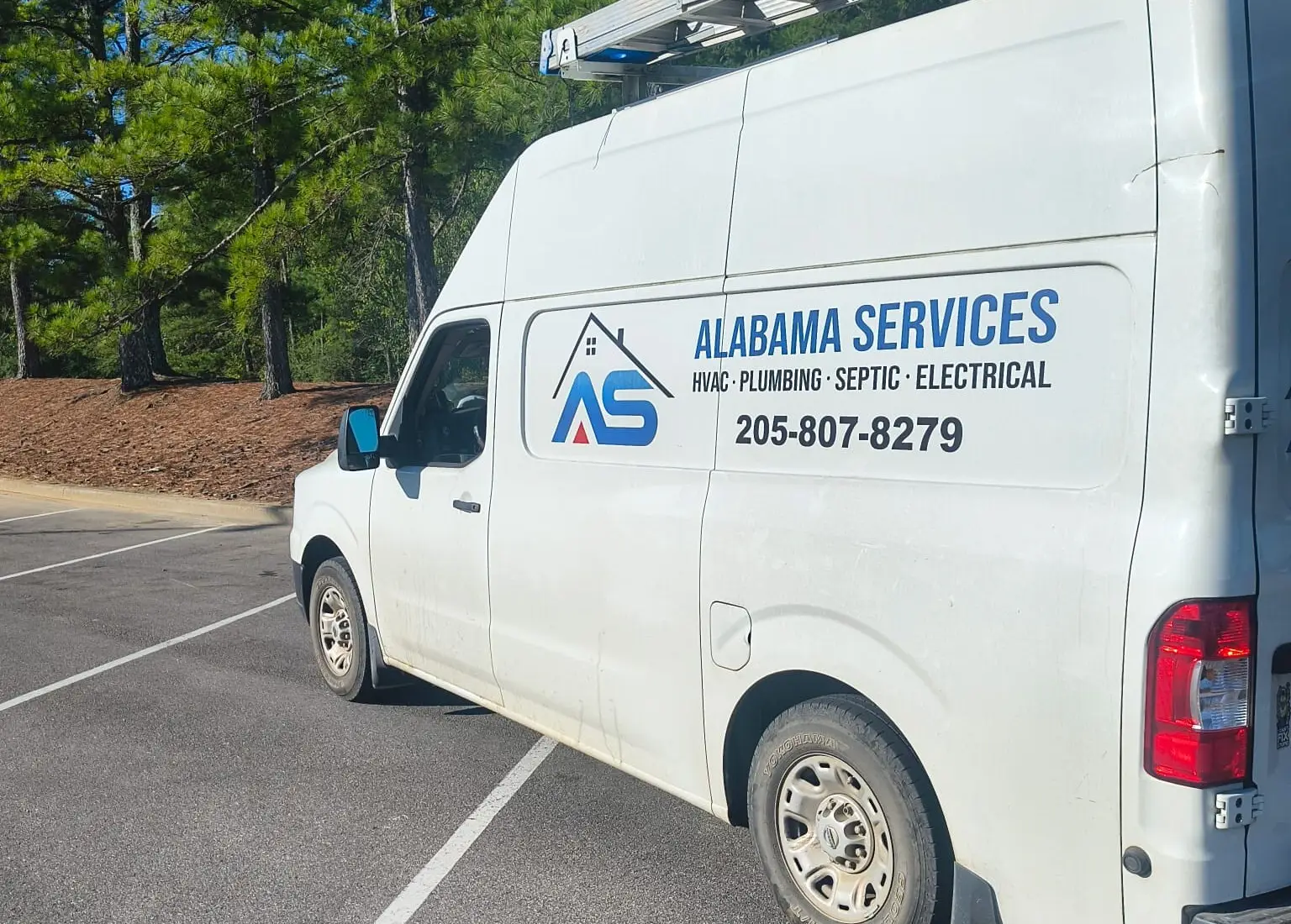 Rear of an Alabama Services work van with the company logo and phone number